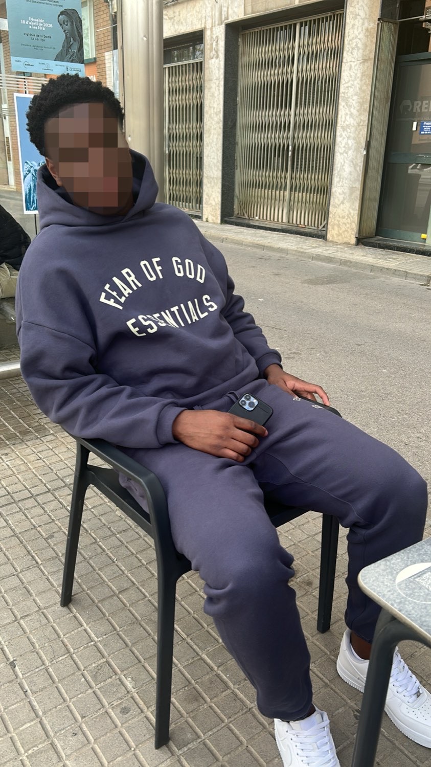 Client sitting outside in a navy Fear of God Essentials hoodie and joggers